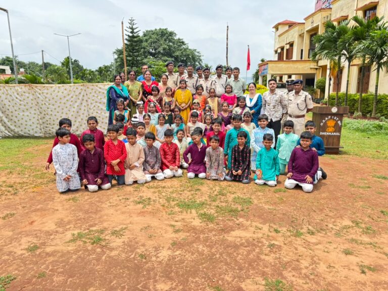 Large group of Indian schoolchildren in colorful outfits posing with teachers and police officers outdoors at a campus.